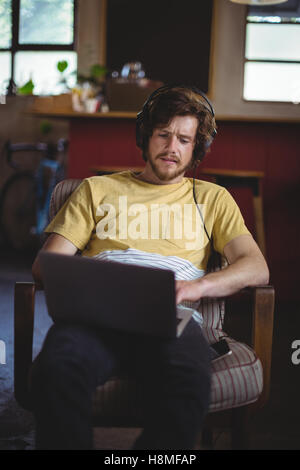 Mechanic listening music while working on laptop Stock Photo