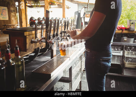 Mid section of bar tender filling beer from bar pump Stock Photo