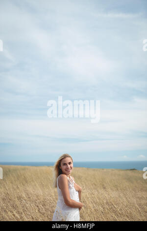 Smiling blonde woman standing in field Stock Photo