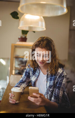 Mechanic using mobile phone while having coffee at counter Stock Photo
