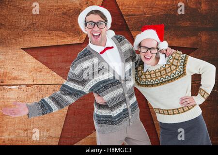 Happy couple in santa hat against digitally generated wooden background Stock Photo