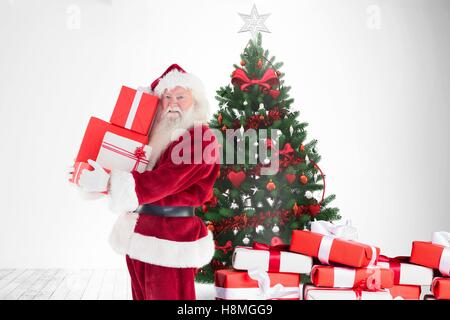 Santa claus holding stack of gift boxes near christmas tree Stock Photo