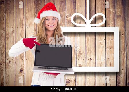 Pretty woman in santa hat and gloves pointing at laptop Stock Photo