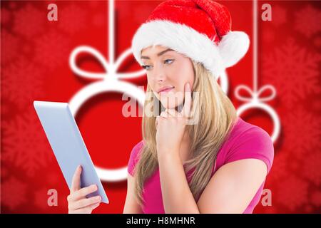 Thoughtful beautiful woman in santa hat using digital tablet Stock Photo