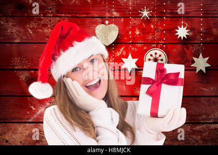 Surprised woman wearing santa hat holding christmas gift Stock Photo
