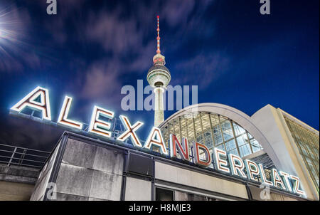 Classic wide-angle view of Alexanderplatz neon sign with famous TV tower and train station at night Berlin, Germany