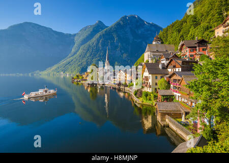 Classic postcard view of famous Hallstatt lakeside town in the Alps with ship in beautiful morning light, Salzkammergut, Austria