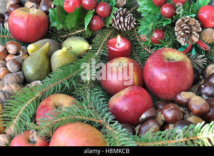 seasonal fruits in Christmas decoration and candles Stock Photo