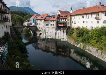 River running through old historic town of Škofja Loka (Slovenia). Bridge over river and reflection of buildings in the water. Stock Photo