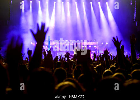 Concert stage with silhouetted hands raised Stock Photo