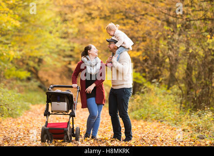 Beautiful young family on a walk in autumn forest. Stock Photo