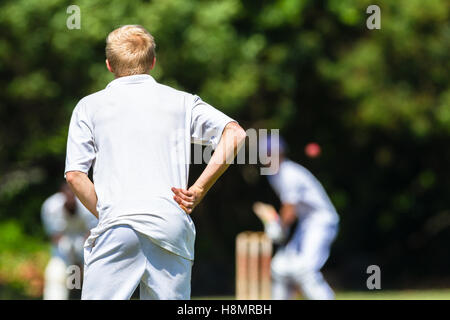 Cricket game teenagers high schools closeup unidentified fielder watching batsman ball action. Stock Photo