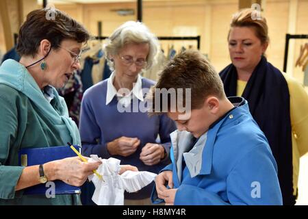 Boy and girl choristers of Wells Cathedral Choir at cassock fitting before rehearsing for evensong. Stock Photo