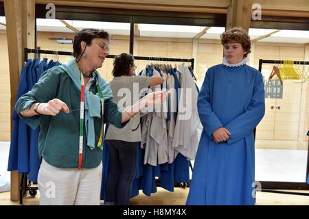 Boy and girl choristers of Wells Cathedral Choir at cassock fitting before rehearsing for evensong. Needlework. Stock Photo