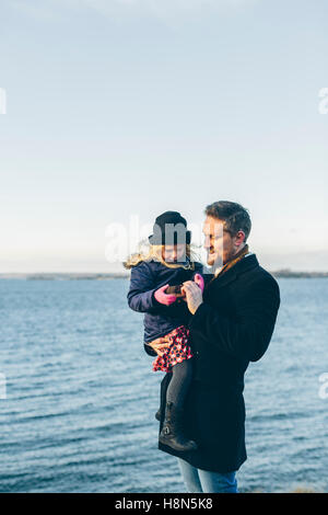 Father with daughter (4-5) standing by sea