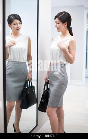 Young Chinese woman examining herself in front of mirror Stock Photo