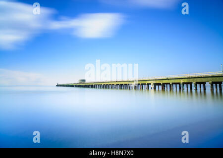 Industrial pier on the sea horizon. Side view. Long exposure photography in a cloudy day. Stock Photo
