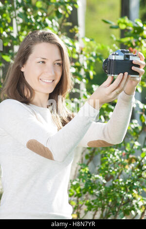 Young woman with old vintage retro camera taking photo Stock Photo