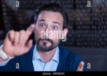 Curious handsome man touching the virtual screen with his finger Stock Photo
