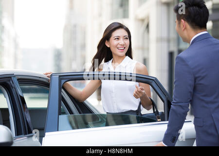 Chinese chauffeur opening car door for a businesswoman Stock Photo