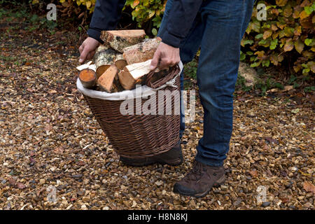 Wicker basket being carried full of cut logs for fire Stock Photo