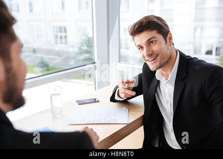 Two happy young businessmen sitting and talking in office Stock Photo