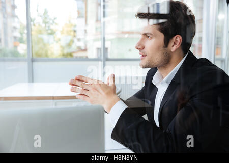 Handsome young businessman in black suit sitting in office Stock Photo
