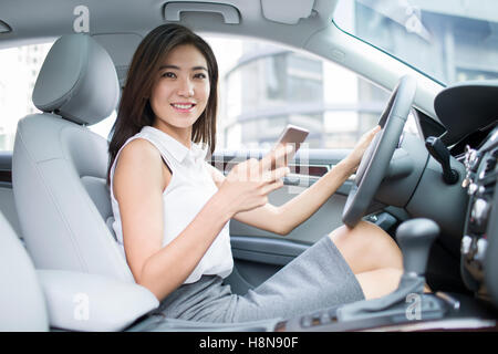 Confident Chinese businesswoman holding smart phone in a car Stock Photo