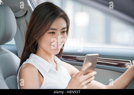 Confident Chinese businesswoman holding smart phone in a car Stock Photo