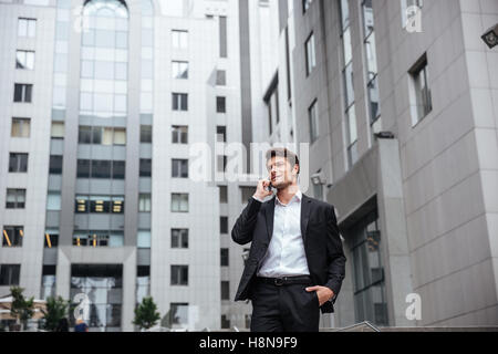 Smiling young businessman talking on mobile phone in the city Stock Photo