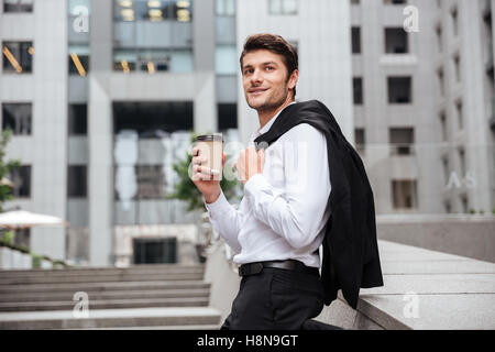 Happy young businessman standing and drinking coffee in the city Stock Photo