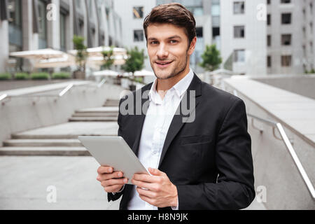 Portrait of attractive young businessman using tablet near business center Stock Photo