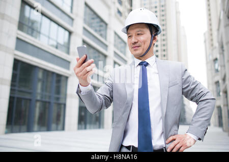 Chinese male architect using smart phone outdoors Stock Photo