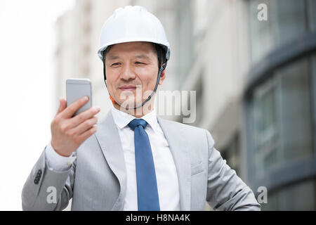Chinese male architect using smart phone outdoors Stock Photo