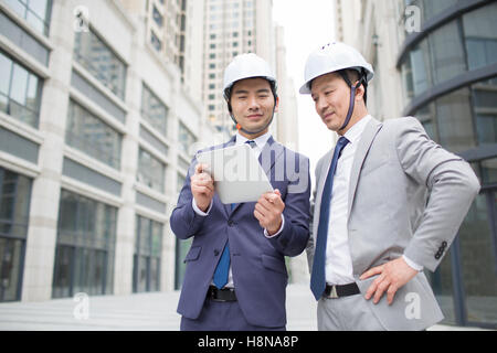 Chinese male architects talking with digital tablet outdoors Stock Photo