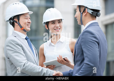 Confident Chinese architects shaking hands outdoors Stock Photo
