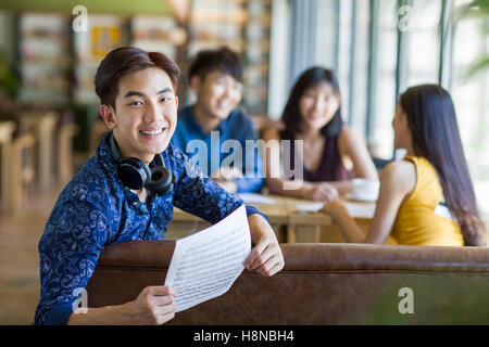 Young Chinese man holding a piece of sheet music Stock Photo