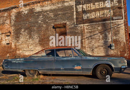 Big old and rusty car next to an old building with a mispelling Stock Photo