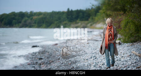 Woman walking alone rocky shore Stock Photo