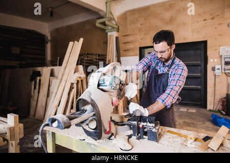 Carpenter Using Circular Saw for wood at his workshop Stock Photo