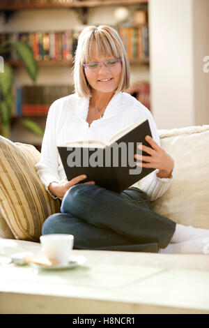 Young woman reading on sofa Stock Photo