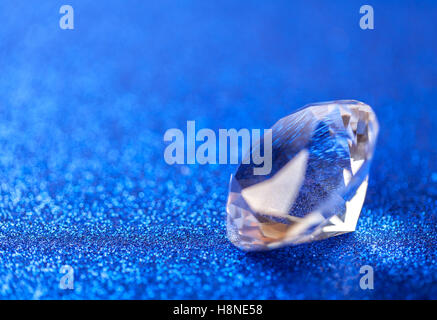 Grand royal pure diamond on blue sparkling sequins background, macro . Big brilliant closeup. Stock Photo