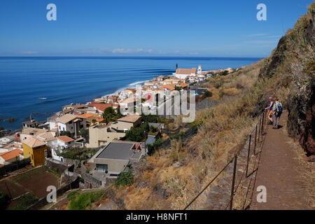 Two young women looking down to the Atlantic shoreline above Paul Do Mar, Madeira, Portugal, while walking down a path Stock Photo