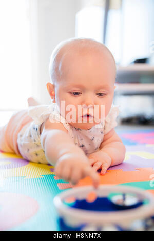 Baby girl with blue eyes playing on mat at floor Stock Photo