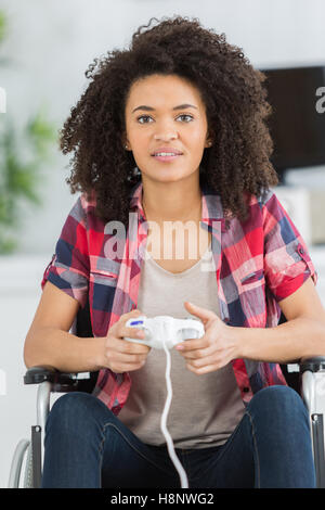 young woman in wheelchair playing video games at home Stock Photo