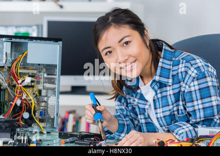 young woman fixing a desktop computer seated at a table Stock Photo