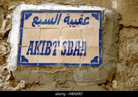 One of the street name markers, Akibt Sbaa,  found on an old Medina wall in the Fez Medina in Fez, Morocco. Stock Photo