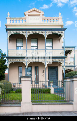 Late Victorian-era double-storey brick home in Melbourne, displaying the characteristically ornate verandah and iron lacework Stock Photo