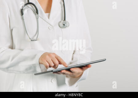 Female doctor in white uniform using tablet computer in hospital office Stock Photo
