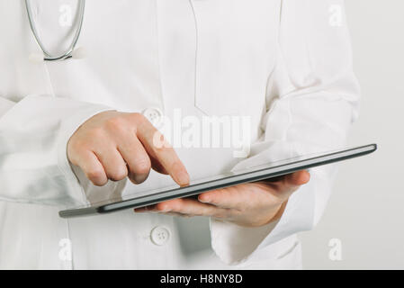 Female doctor in white uniform using tablet computer in hospital office Stock Photo